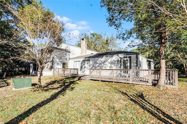 rear view of house featuring a yard, a chimney, and a wooden deck