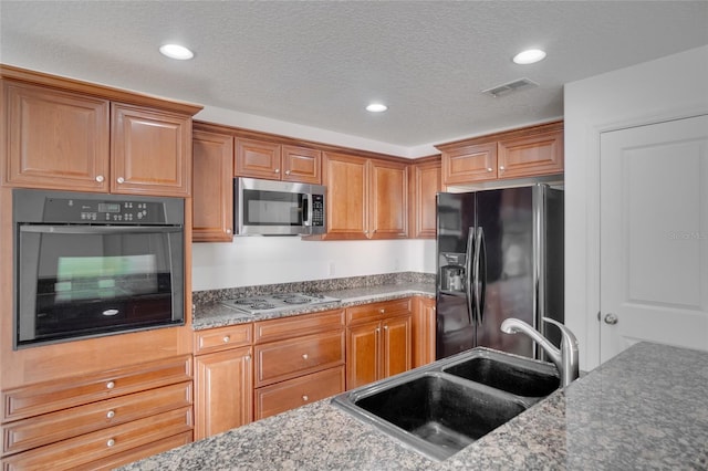 kitchen with stone counters, sink, a textured ceiling, and black appliances