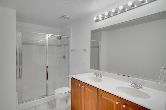 bathroom with toilet, a textured ceiling, vanity, a shower with door, and tile patterned flooring