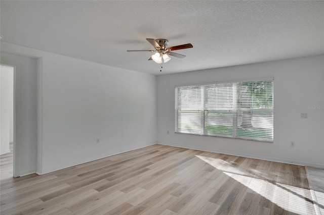 spare room featuring light wood-type flooring, a textured ceiling, and ceiling fan