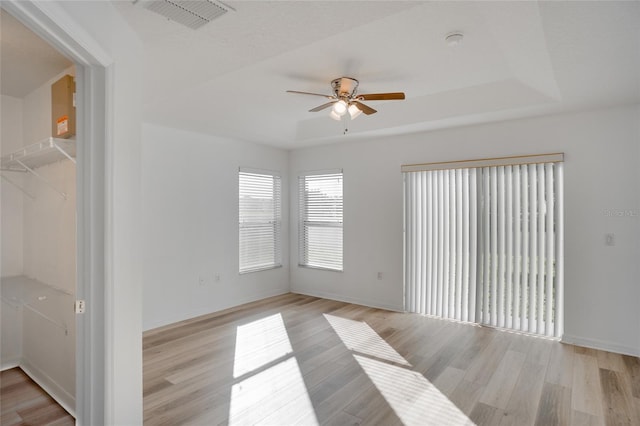 spare room featuring light hardwood / wood-style flooring, a raised ceiling, and ceiling fan