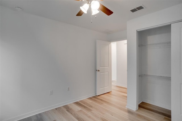 unfurnished bedroom with light wood-type flooring, ceiling fan, and a closet