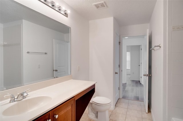 bathroom featuring tile patterned floors, toilet, a textured ceiling, and vanity