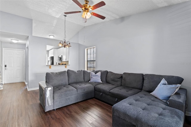 living room featuring a textured ceiling, ceiling fan with notable chandelier, vaulted ceiling, and dark wood-type flooring