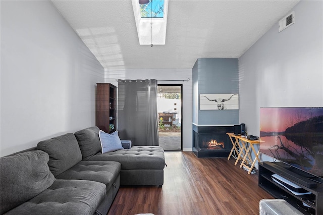 living room featuring a textured ceiling, dark hardwood / wood-style flooring, and lofted ceiling with skylight