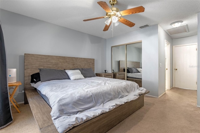 carpeted bedroom with ceiling fan, a closet, and a textured ceiling