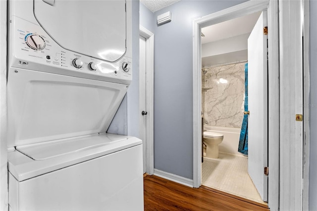 washroom with stacked washer and dryer, a textured ceiling, and dark hardwood / wood-style floors