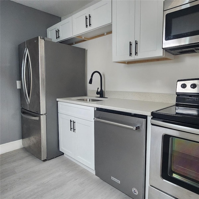 kitchen with white cabinetry, sink, appliances with stainless steel finishes, and light hardwood / wood-style flooring