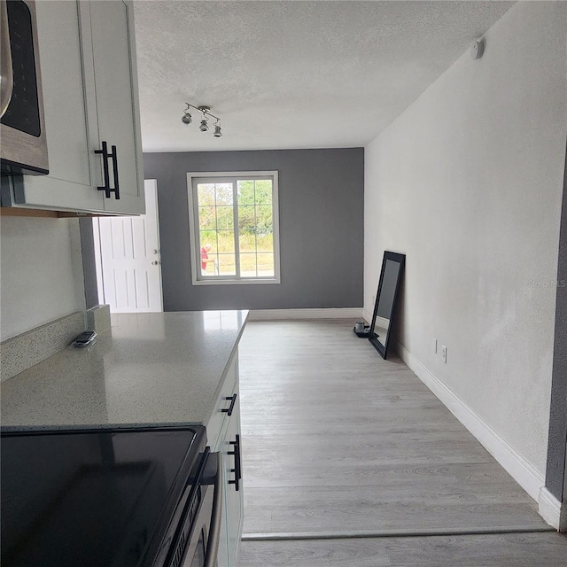 kitchen featuring light wood-type flooring, a textured ceiling, and black / electric stove