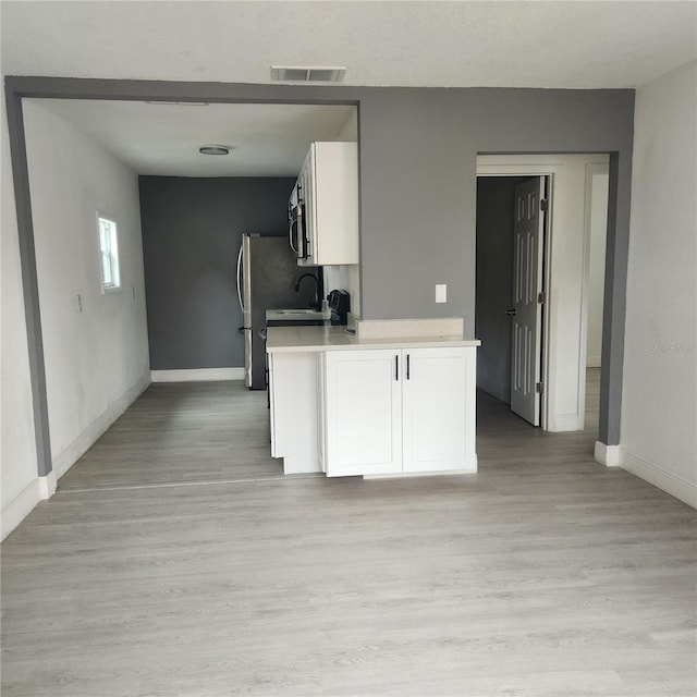 kitchen with white cabinets, light wood-type flooring, and sink