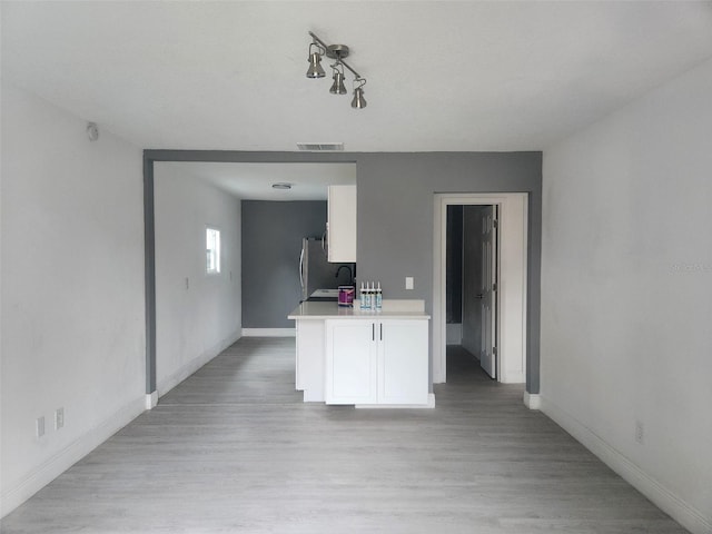 kitchen with white cabinets, stainless steel fridge, light hardwood / wood-style floors, and kitchen peninsula