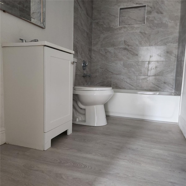 full bathroom featuring hardwood / wood-style floors, vanity, toilet, and bathtub / shower combination