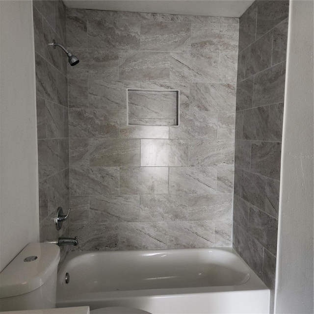 bathroom with tiled shower / bath combo and toilet