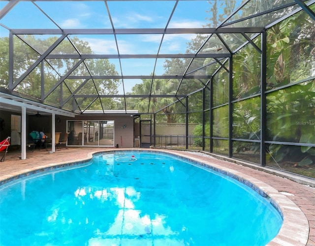 view of pool with glass enclosure and a patio area