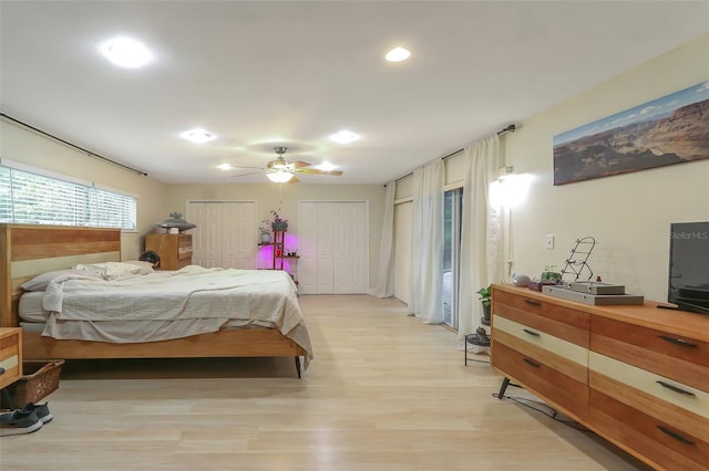 bedroom with two closets, light hardwood / wood-style floors, and ceiling fan