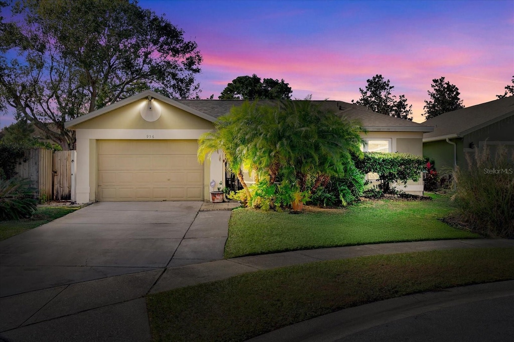 single story home with a garage and a lawn