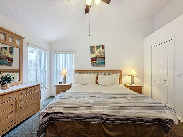 bedroom featuring ceiling fan, dark colored carpet, a textured ceiling, vaulted ceiling, and a closet