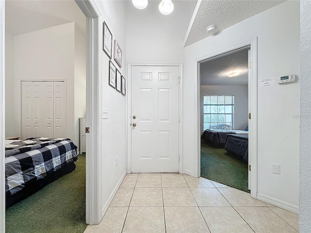 hall featuring a textured ceiling and light colored carpet