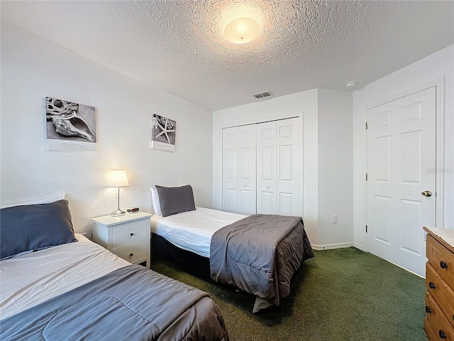 bedroom featuring a textured ceiling, dark carpet, and a closet