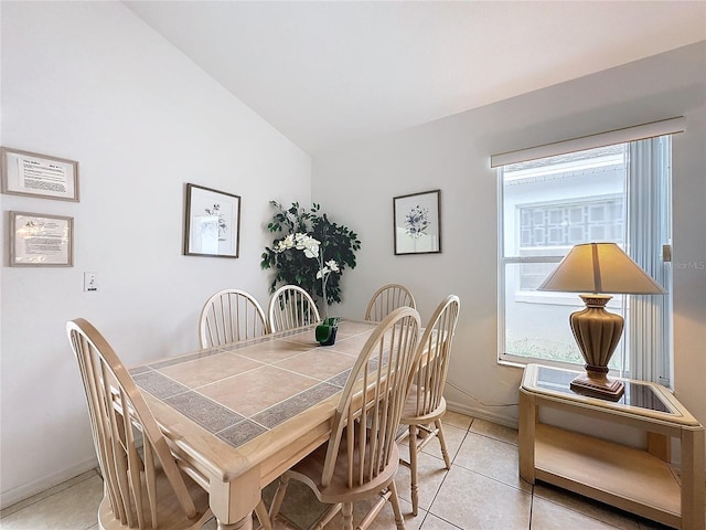 dining space featuring vaulted ceiling and light tile patterned flooring