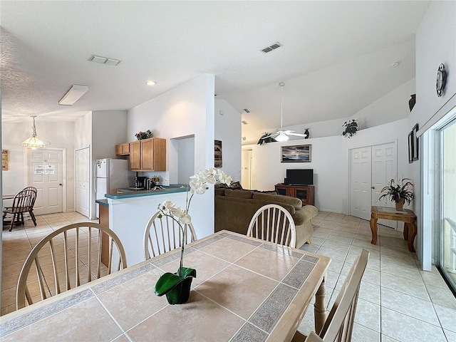 dining area with ceiling fan with notable chandelier, light tile patterned flooring, and lofted ceiling