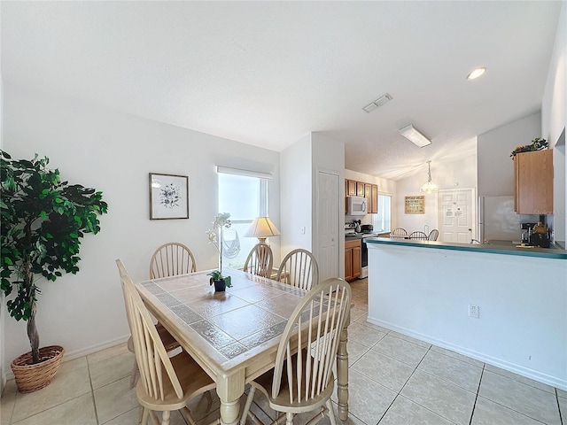 dining area featuring light tile patterned floors and lofted ceiling