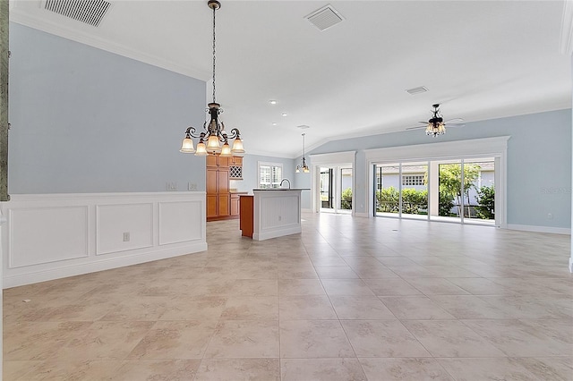 unfurnished living room with ceiling fan with notable chandelier, a healthy amount of sunlight, lofted ceiling, and ornamental molding