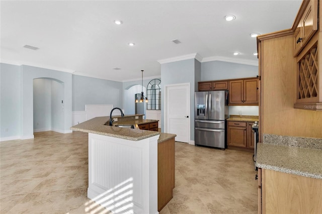 kitchen with sink, light stone counters, crown molding, stainless steel fridge, and pendant lighting