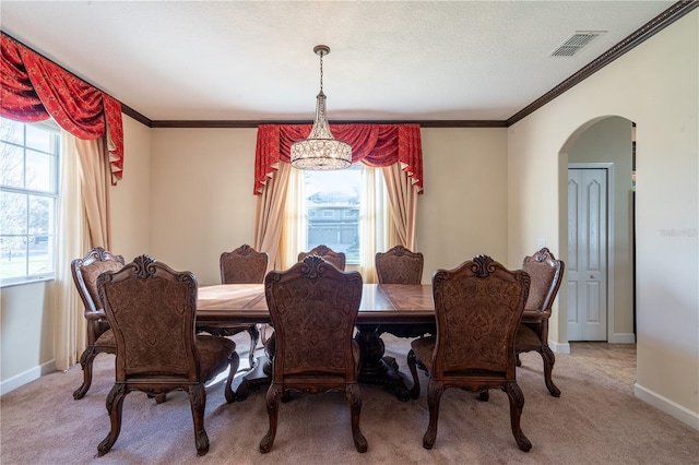 carpeted dining area with a notable chandelier, a healthy amount of sunlight, and ornamental molding