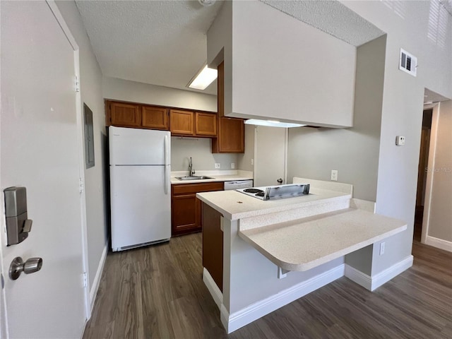 kitchen featuring sink, dark wood-type flooring, kitchen peninsula, white appliances, and a breakfast bar