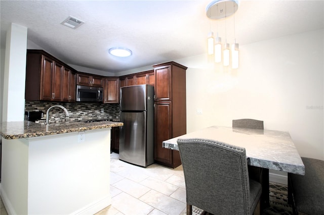 kitchen with pendant lighting, kitchen peninsula, stainless steel appliances, and light tile patterned floors