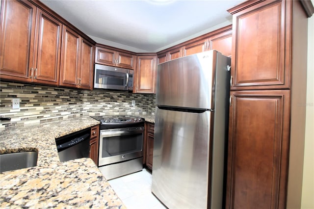 kitchen with sink, tasteful backsplash, light stone counters, light tile patterned floors, and appliances with stainless steel finishes