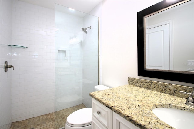 bathroom with a tile shower, vanity, and toilet