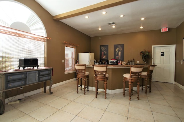 kitchen featuring a kitchen bar, white refrigerator, and plenty of natural light