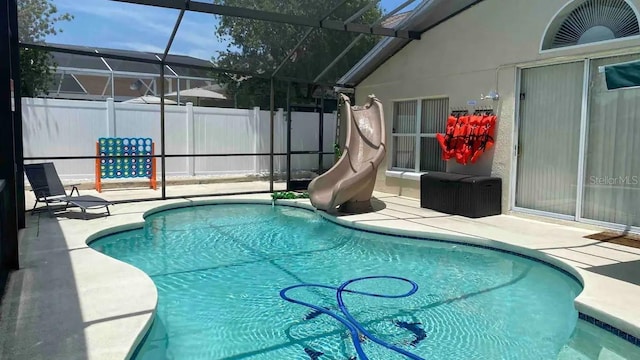 view of swimming pool with glass enclosure, a patio area, and a water slide