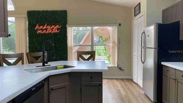 kitchen featuring kitchen peninsula, appliances with stainless steel finishes, light wood-type flooring, sink, and gray cabinets