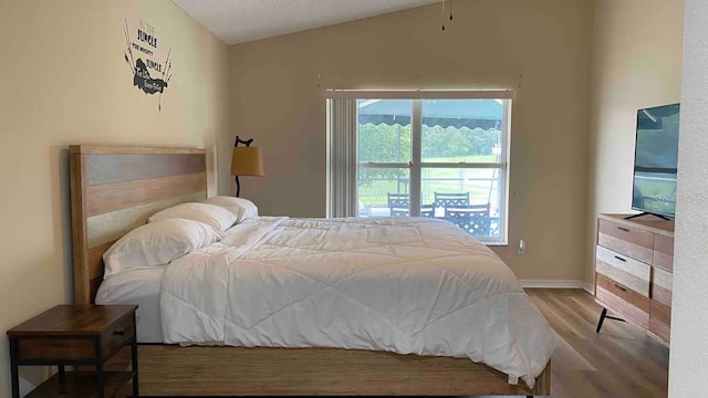 bedroom featuring a textured ceiling, vaulted ceiling, and hardwood / wood-style flooring