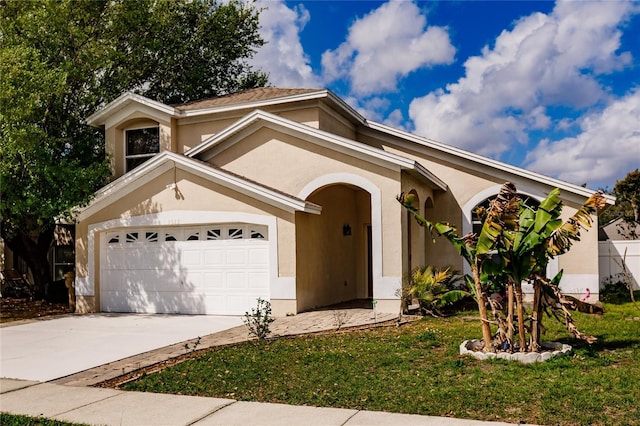 view of front of home with a garage, a front lawn, concrete driveway, and stucco siding