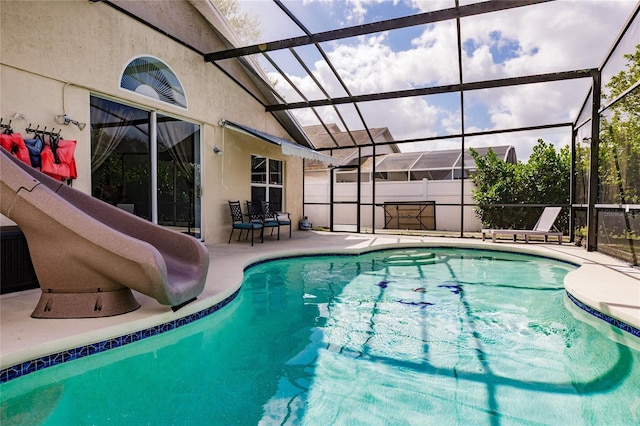 view of pool with a water slide, a patio area, and a lanai