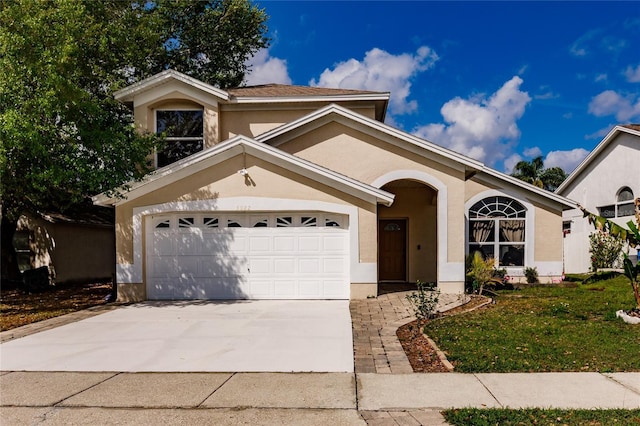 view of front of property with a garage, a front yard, driveway, and stucco siding