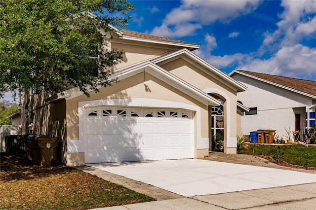 view of front of home with a garage, driveway, and stucco siding