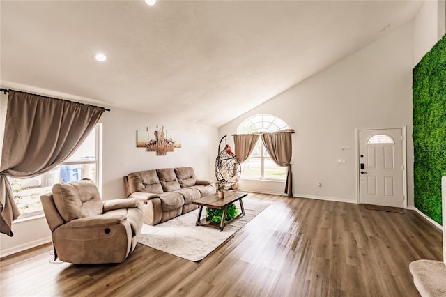 living room featuring high vaulted ceiling, baseboards, and wood finished floors