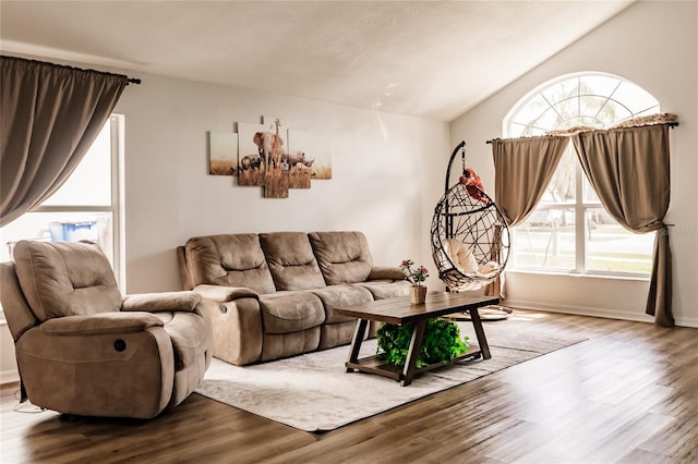 living room featuring lofted ceiling, plenty of natural light, wood finished floors, and baseboards