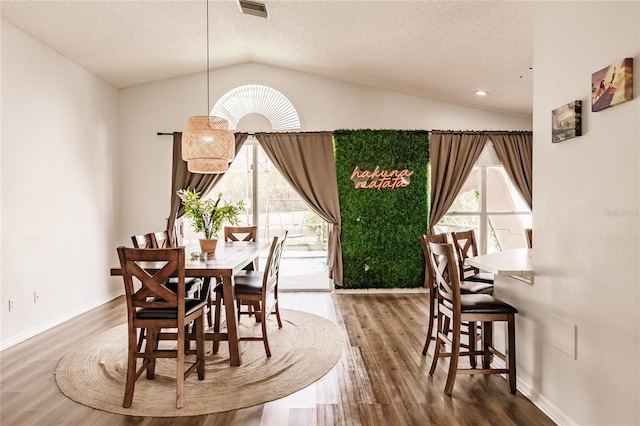 dining room featuring lofted ceiling, a textured ceiling, baseboards, and wood finished floors