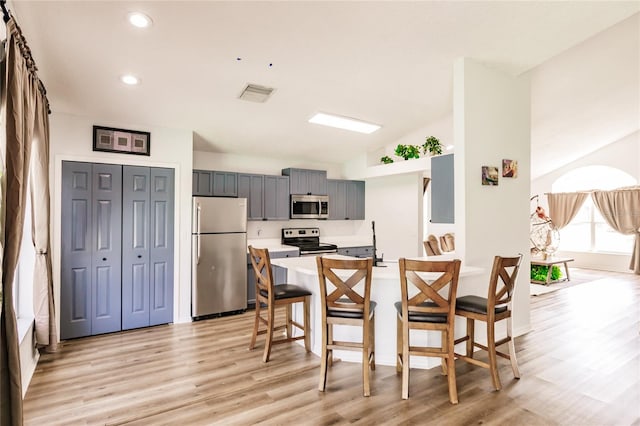 kitchen featuring light wood finished floors, visible vents, appliances with stainless steel finishes, a kitchen breakfast bar, and light countertops