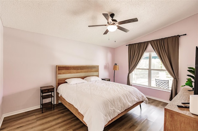 bedroom with vaulted ceiling, a textured ceiling, wood finished floors, and baseboards