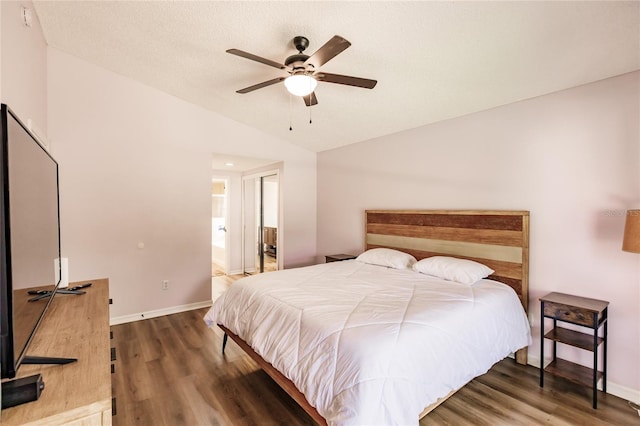 bedroom featuring baseboards, a ceiling fan, lofted ceiling, wood finished floors, and a textured ceiling
