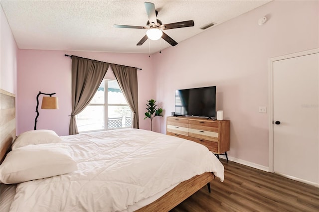 bedroom featuring baseboards, visible vents, wood finished floors, vaulted ceiling, and a textured ceiling