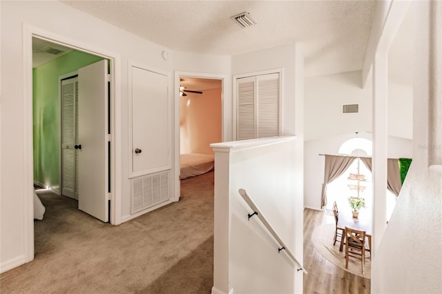 hallway with visible vents, carpet floors, and an upstairs landing