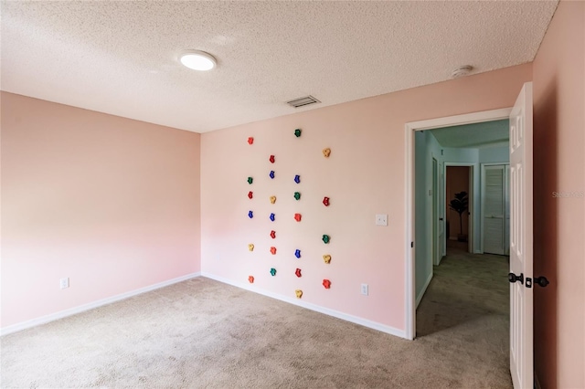 empty room featuring carpet floors, visible vents, a textured ceiling, and baseboards